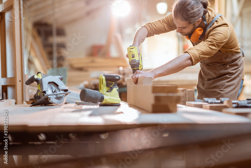 Φωτογραφία Carpenter working with modern cordless tools and wooden bars on the workbench at