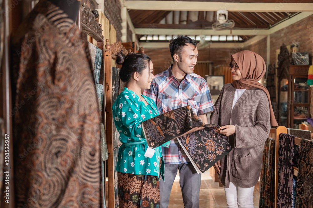 Obraz premium a woman showing the traditional batik cloth she sells to customer