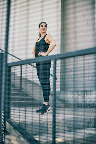 Young fit gorgeous sportswoman standing with hands on hips and resting after running.