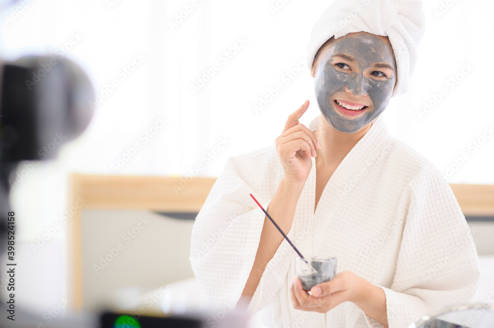 Video camera filming woman in white bathrobe applying a face mask for movie, behind the scenes of shoot Video camera filming woman in white bathrobe applying a face mask for movie, behind the scenes of shoot