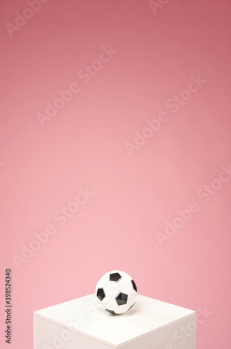 Soccer ball on the white cub with a pink background. Vertical shot with a copyspace at the top.