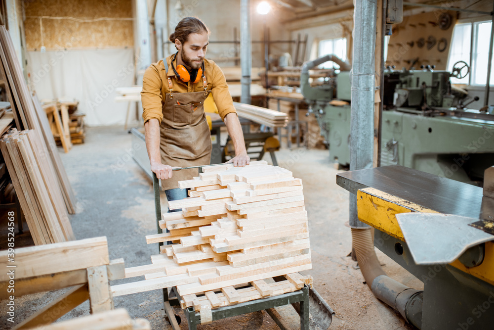 Carpentry worker pushing cart full of wooden planks at the joinery warehouse Carpentry worker pushing cart full of wooden planks at the joinery warehouse