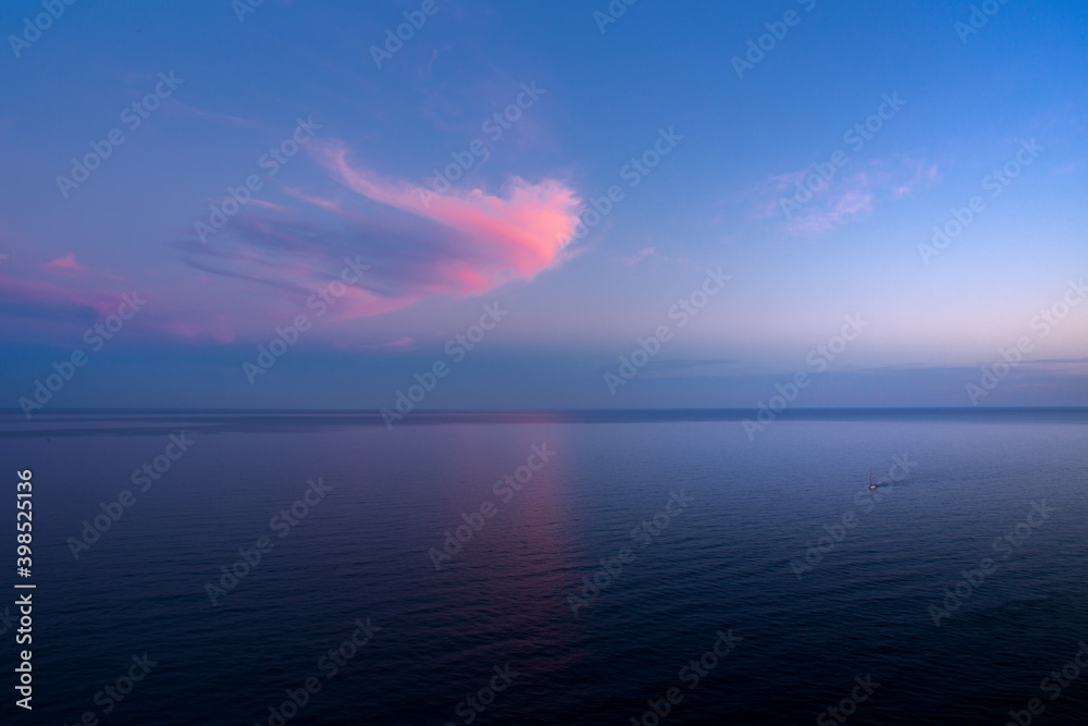 Sunset on the sea and a beautiful pink cloud against a blue sky.