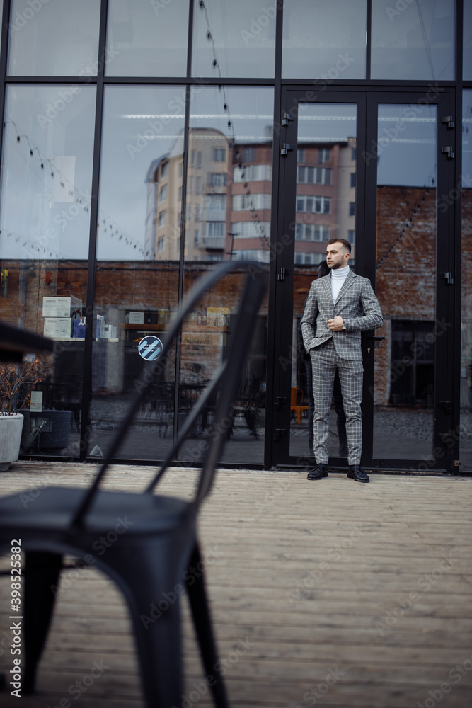 Full length body size photo of stylish entrepreneur walking outside cafe in checkered suit coat scarf looking at side