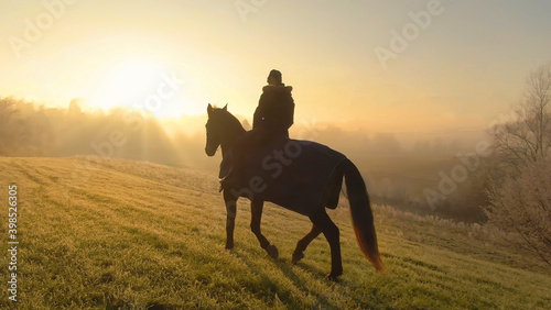 Golden sunbeams peer through fog for horseback rider to explore the countryside. © helivideo