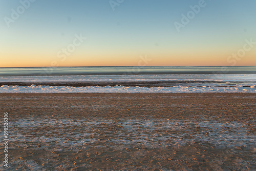 Winter landscape in beach  coastline with cracked ice and opened sea water.