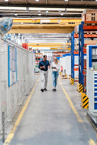 Wallpaper Mural Businesswoman discussing with male colleague while walking in factory Torontodigital.ca