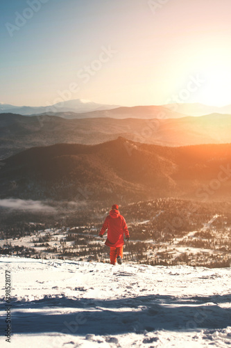 Woman wering ski outfit looking at the mountains in snow. Ski resort. Beautiful view of the mountains.