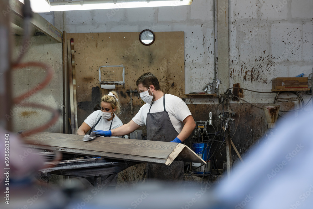 Carpenter team polishing wood while standing at factory Carpenter team polishing wood while standing at factory