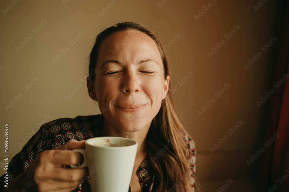 Female entrepreneur drinking coffee while sitting in office against wall Female entrepreneur drinking coffee while sitting in office against wall