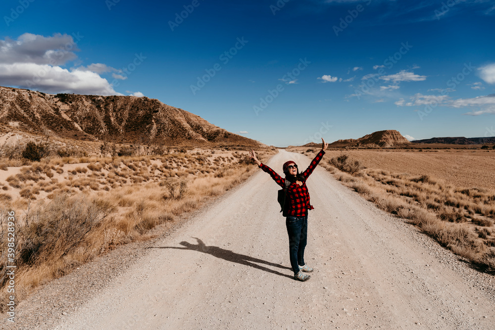 Spain, Navarre, Female tourist standing with raised arms in middle of empty dirt road in Bardenas Reales Spain, Navarre, Female tourist standing with raised arms in middle of empty dirt road in Bardenas Reales