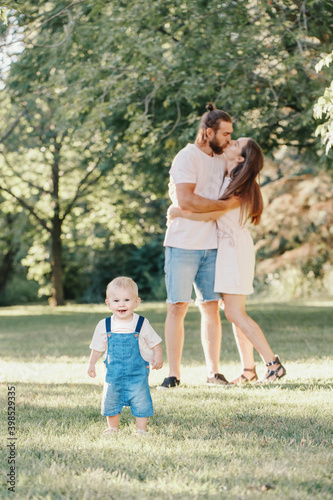 Happy family. Mother and father with baby boy in park outdoors. Family Caucasian mom and dad with son walking hugging in park on summer day. Family authentic lifestyle concept.
