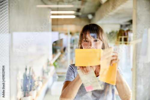 Mature woman sticking sticky notes on glass material photo