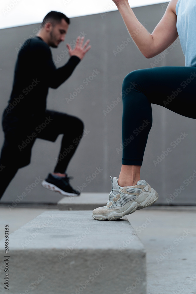 Young couple exercising together against wall Young couple exercising together against wall
