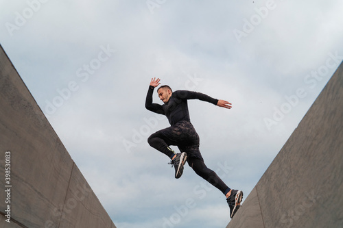 Sportsman jumping on wall against sky photo