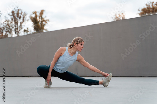 Woman stretching leg while doing warm up exercise against wall