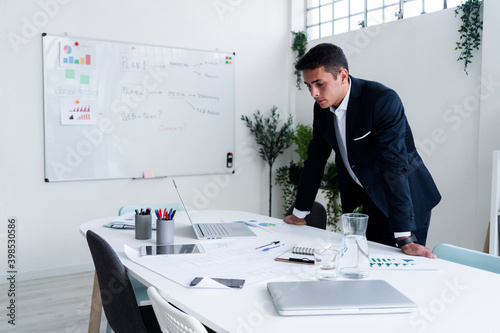 Handsome male professional leaning on desk while planning strategy at creative office