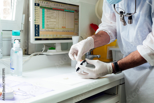 Male dentist preparing denture while standing at clinic