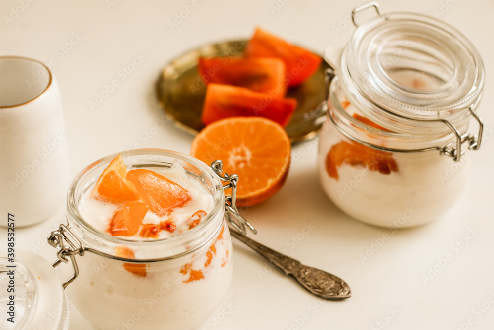 Homemade orange yoghurt in glass jar on white background. Healty nutrition concept. Closeup Homemade orange yoghurt in glass jar on white background. Healty nutrition concept. Closeup