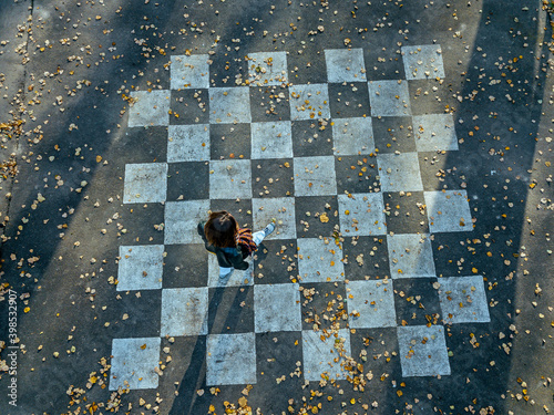 Mid adult woman walking on chessboard painted on asphalt