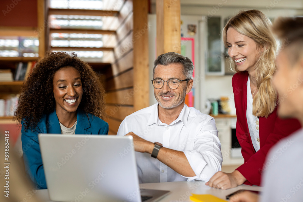 Smiling business people using laptop while working together in meeting at office Smiling business people using laptop while working together in meeting at office