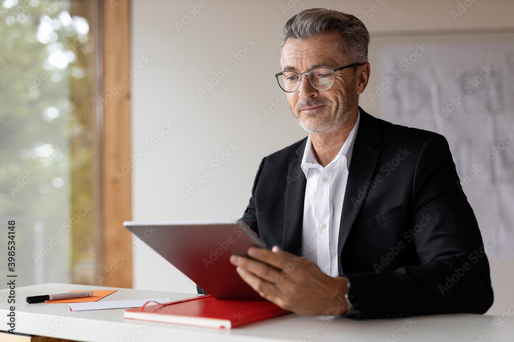 Mature businessman using digital tablet while sitting at home Mature businessman using digital tablet while sitting at home