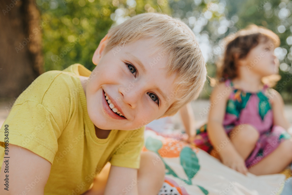 Cute kids sitting at beach on sunny day Cute kids sitting at beach on sunny day