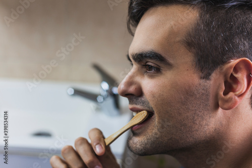 Young man brushing teeth with bamboo toothbrush photo