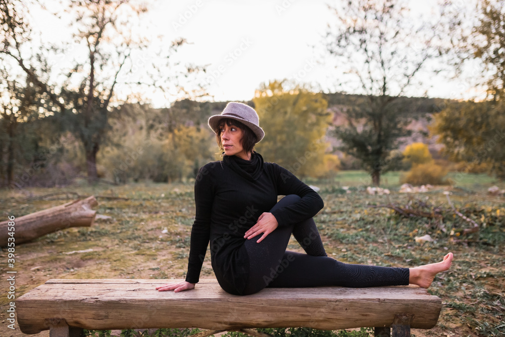 Fototapeta premium Woman practicing yoga and stretching on the park bench