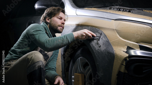 The man works in a tuning studio. Car tuning. The building of the car's arch layout.