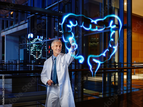 Smiling male gastroenterologist examining large intestine with light painting at hospital photo