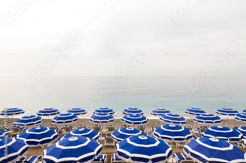 Empty deck chairs and beach umbrellas along coastal beach of French Riviera