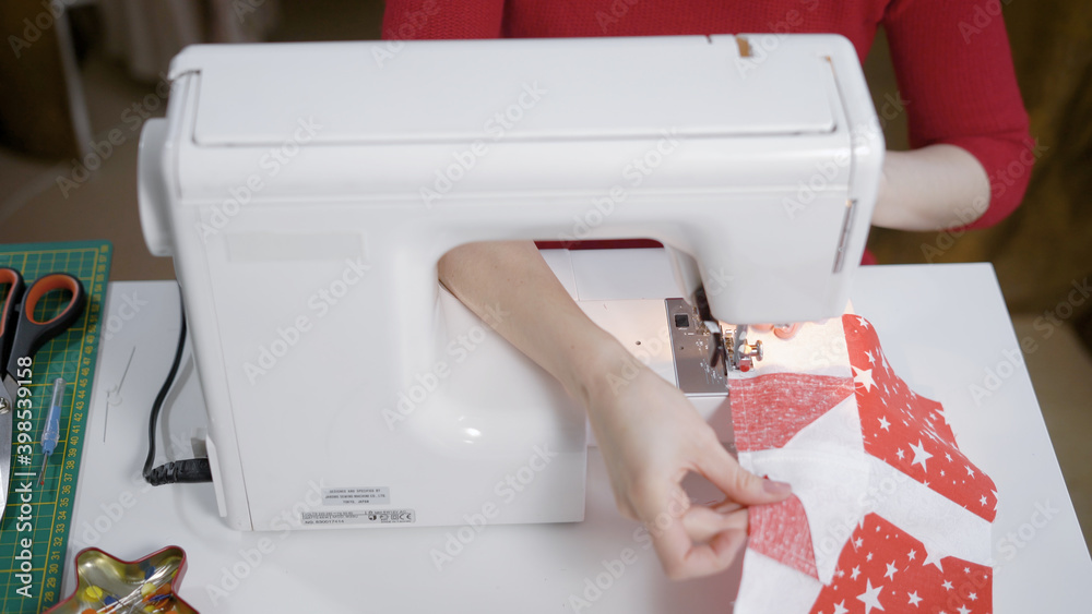 Woman's hands with dress at sewing machine close up
