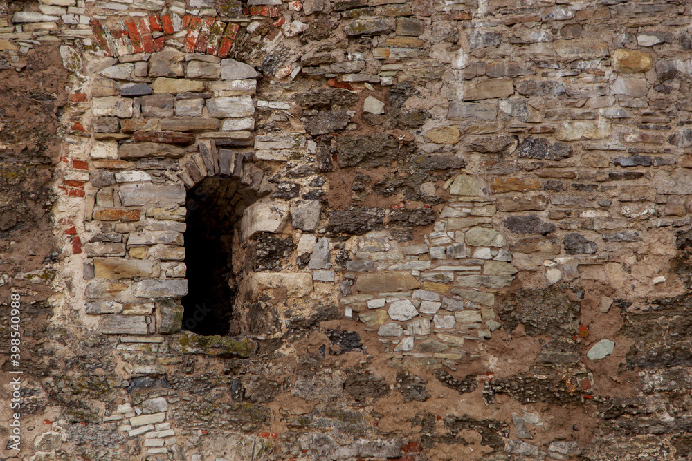 Medieval old stone wall, with a small window, defensive structure, fort. Natural texture, a copy space.