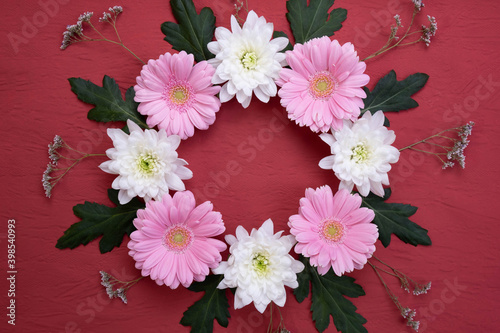 herbs, leaves, flowers of pale pink gerbera and white chrysanthemum are folded in a circle