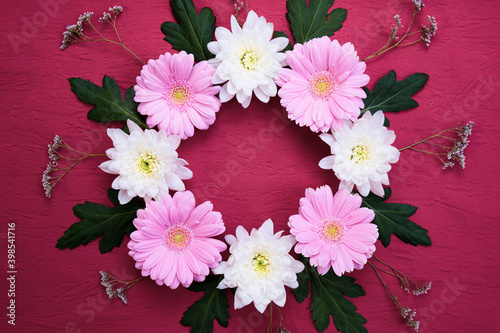 leaves, flowers of pale pink gerbera and white chrysanthemum are folded in a circle