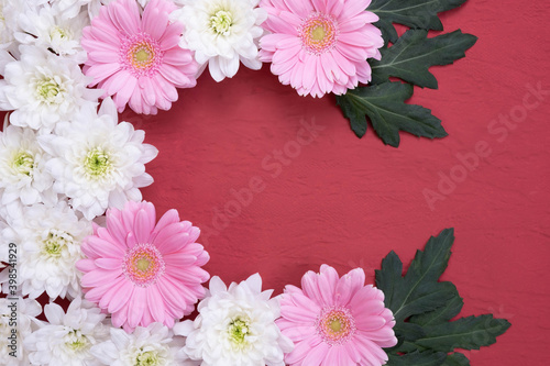 leaves, flowers of pink gerbera and chrysanthemum folded in the form of a frame