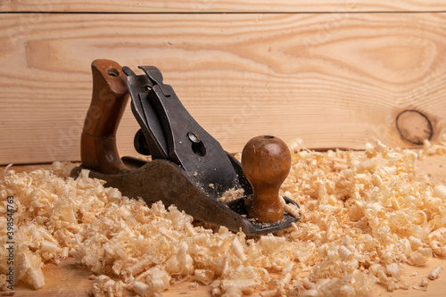 an old carpenter plane on a wooden background with shavings