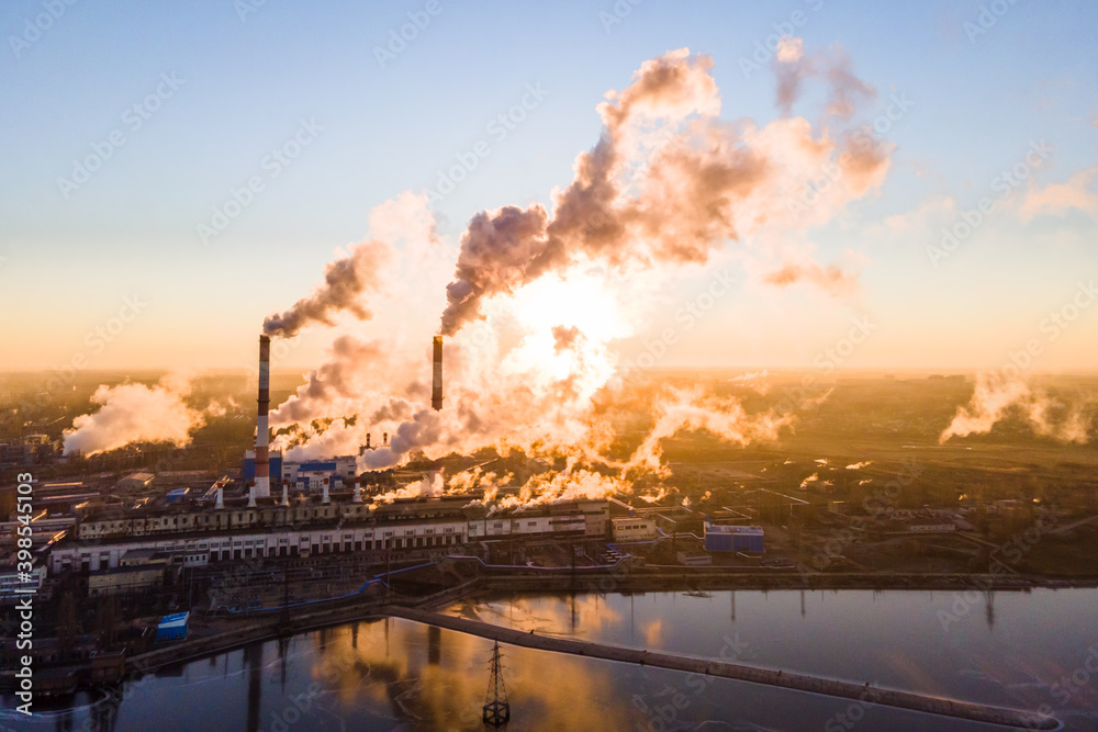 Smoke from chimney factory at sunrise. Pollution by industry smokestack against a red sunrise Smoke from chimney factory at sunrise. Pollution by industry smokestack against a red sunrise