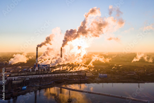 Smoke from chimney factory at sunrise. Pollution by industry smokestack against a red sunrise