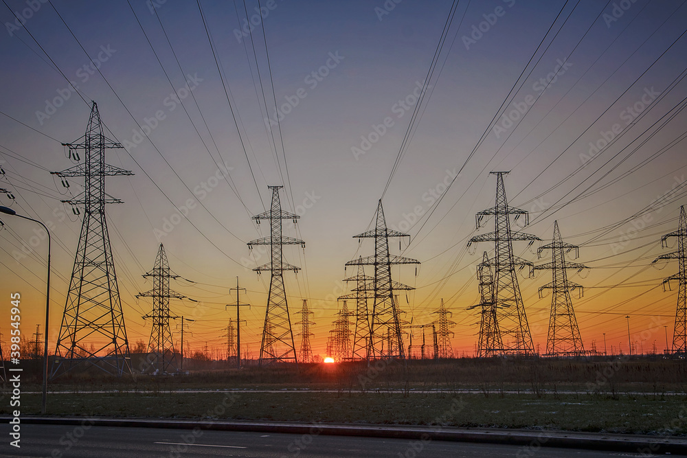 Silhouettes of a high-voltage electric tower against the background of sunrise and sky. Power line.
