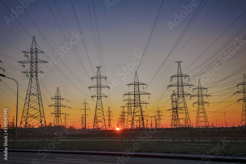 Silhouettes of a high-voltage electric tower against the background of sunrise and sky. Power line.