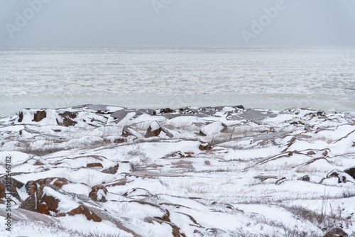 Arctic tundra landscape in Churchill, Manitoba. Hudson Bay with ice, icy waves and tides. Ocean water with rocks, snow and cold, freezing conditions. 