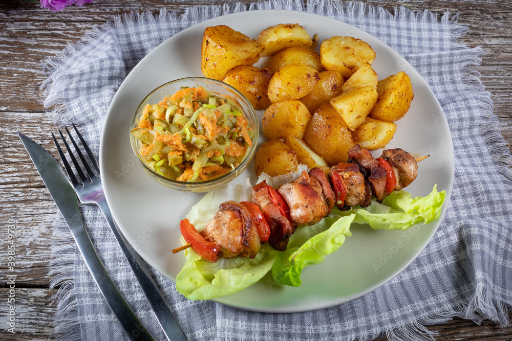 Shish kebab served with roasted potatoes and salad.