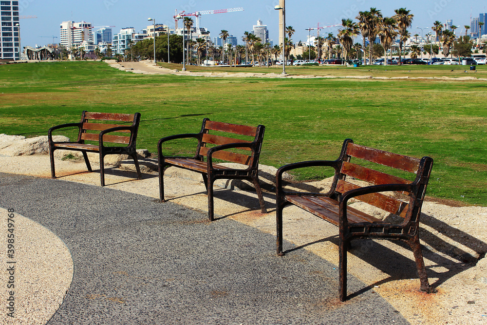 Benches on the promenade on the beach in tel Aviv against the background of the city. The Givat Aliya Beach. Tel Aviv, Israel.