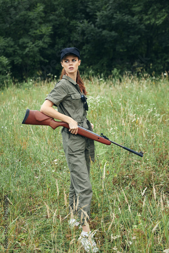 Woman soldier A woman with a weapon in her hands in a green jumpsuit look to the side 