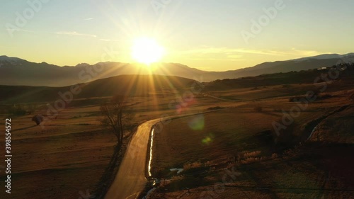 Aerial shot of a long isolated country road surrounded by fields during the sunrise, Pyrenees, france