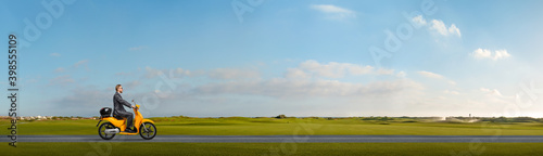 Canvas Print office worker or businessman sits and goes on motor scooter outdoor