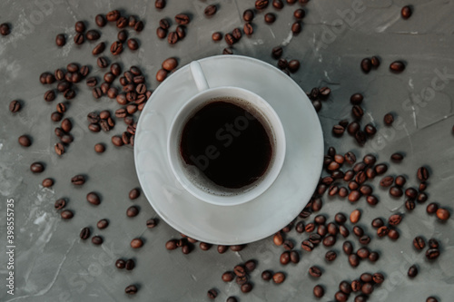 cup of coffee on a gray concrete background. coffee beans lie around. © roman38russ