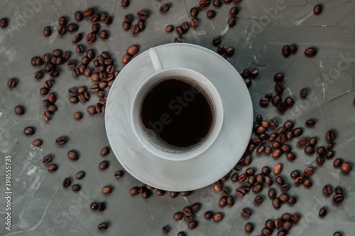 cup of coffee on a gray concrete background. coffee beans lie around.